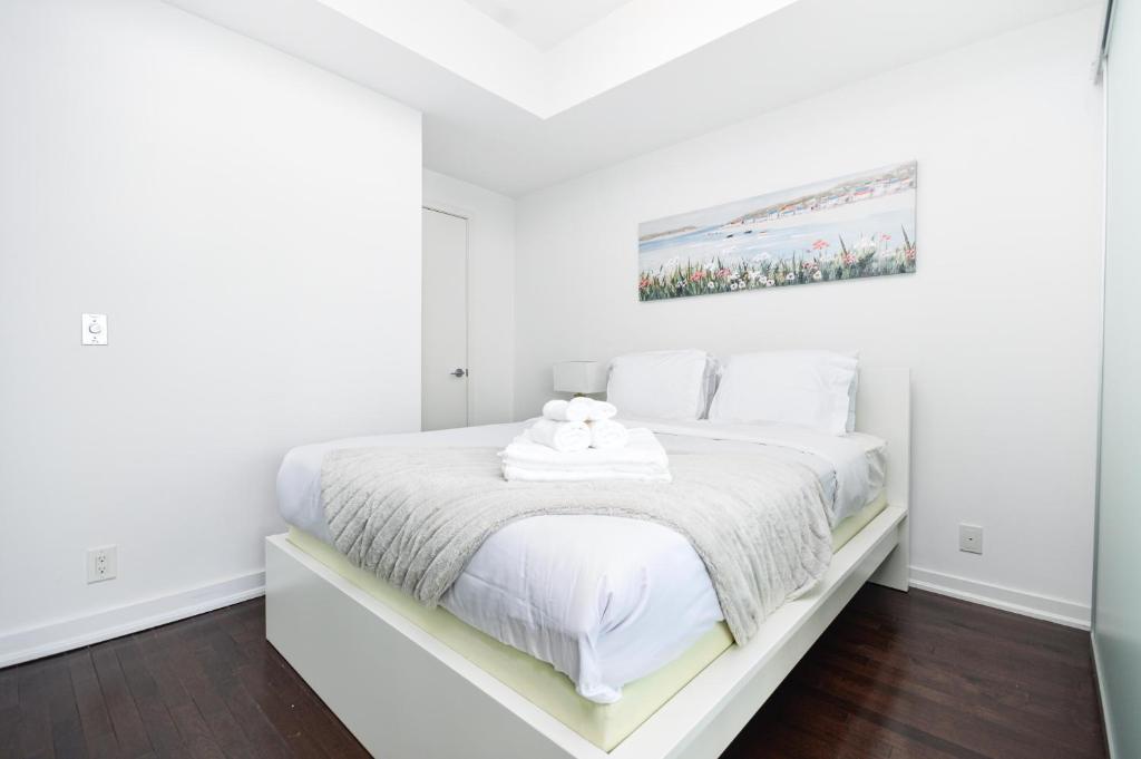 ミシサガにあるDowntown Toronto Condo walk to CN Tower and Rogers centerの白いシーツが敷かれた大きなベッドのある白い寝室