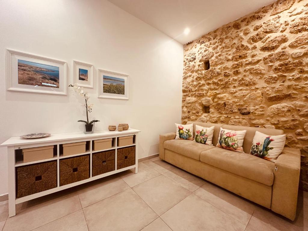 a living room with a couch and a stone wall at Tannur Del Carmine in Noto