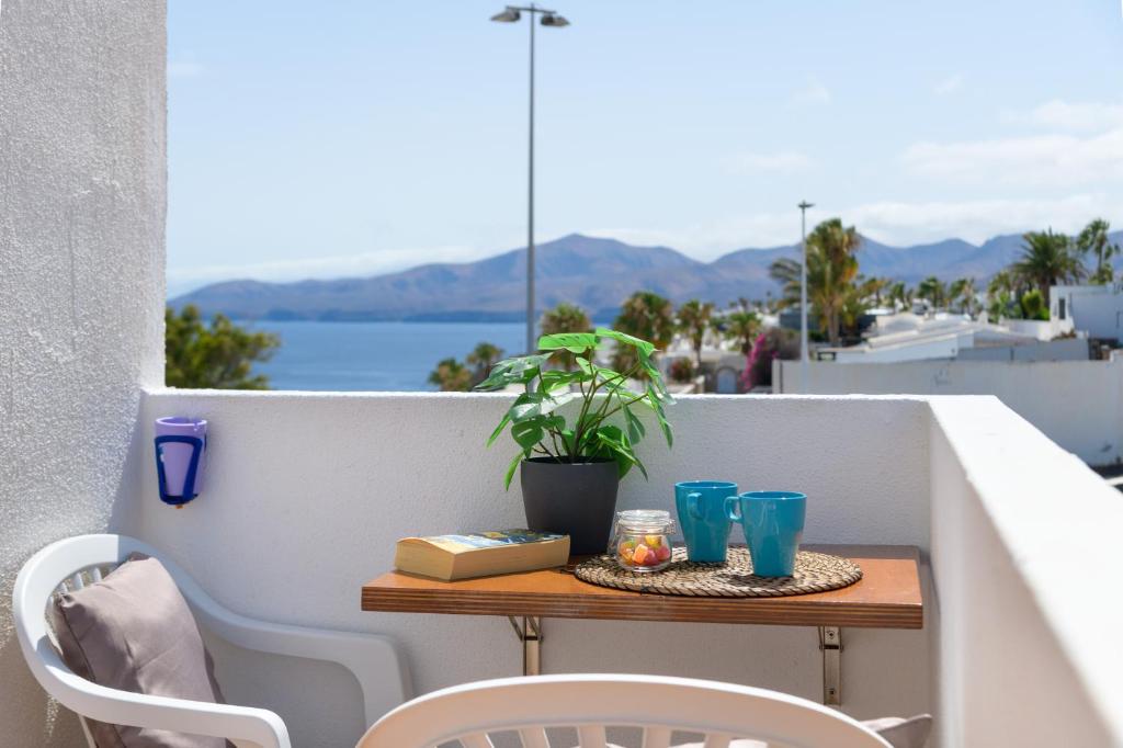 a table on a balcony with a plant and blue glasses at Apartamentos Bellavista in Puerto del Carmen