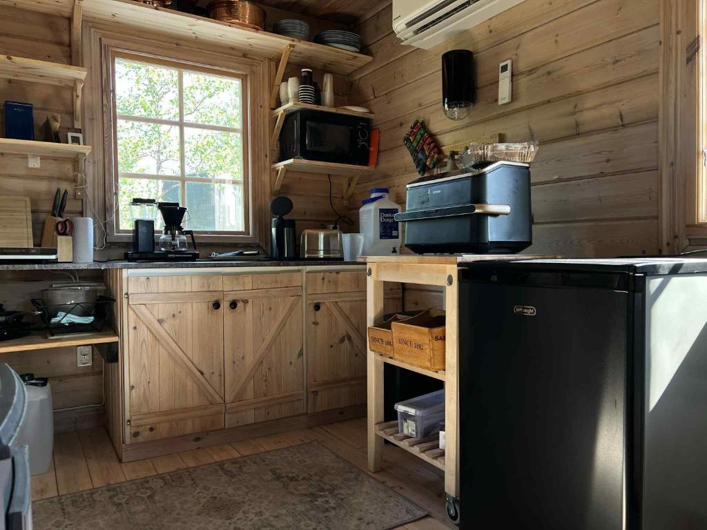 a kitchen with wooden cabinets and a black refrigerator at Wilderness cottage 6 people in Kiruna