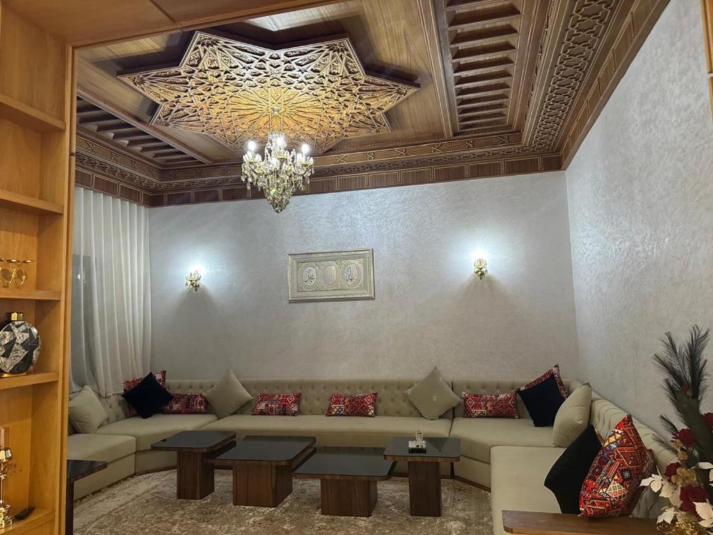 Una sala de estar con un sofá y una lámpara de araña. en Villa à louer, en Oulad Akkou