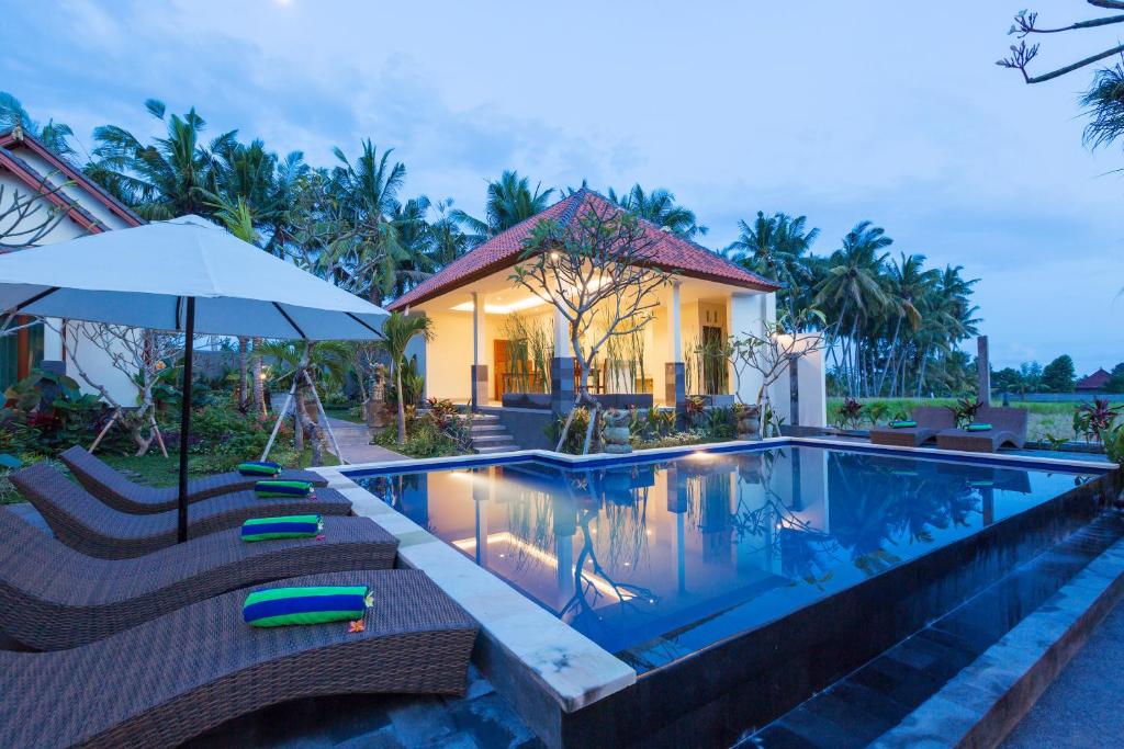 a swimming pool with chairs and an umbrella next to a house at Sisin Ubud View in Ubud