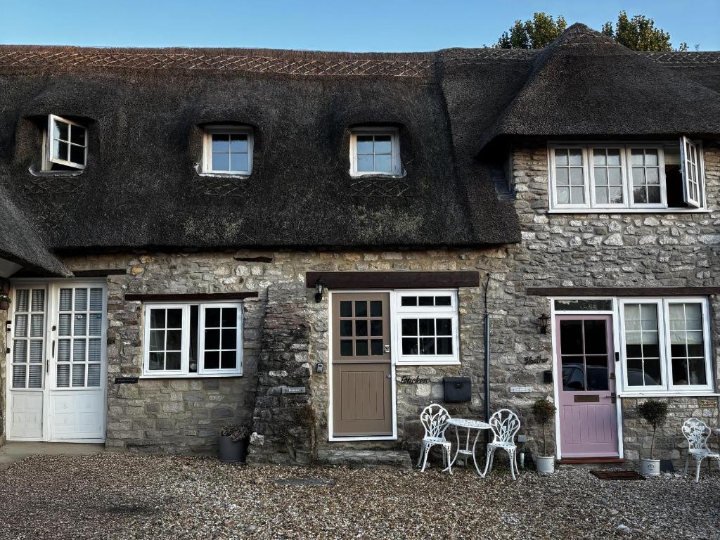 a stone house with two benches in front of it at Bracken Cottage in Weymouth