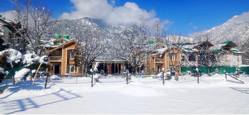 a snow covered yard with a house and trees at Lidder view The best River side Resort in Pahalgam in Pahalgām