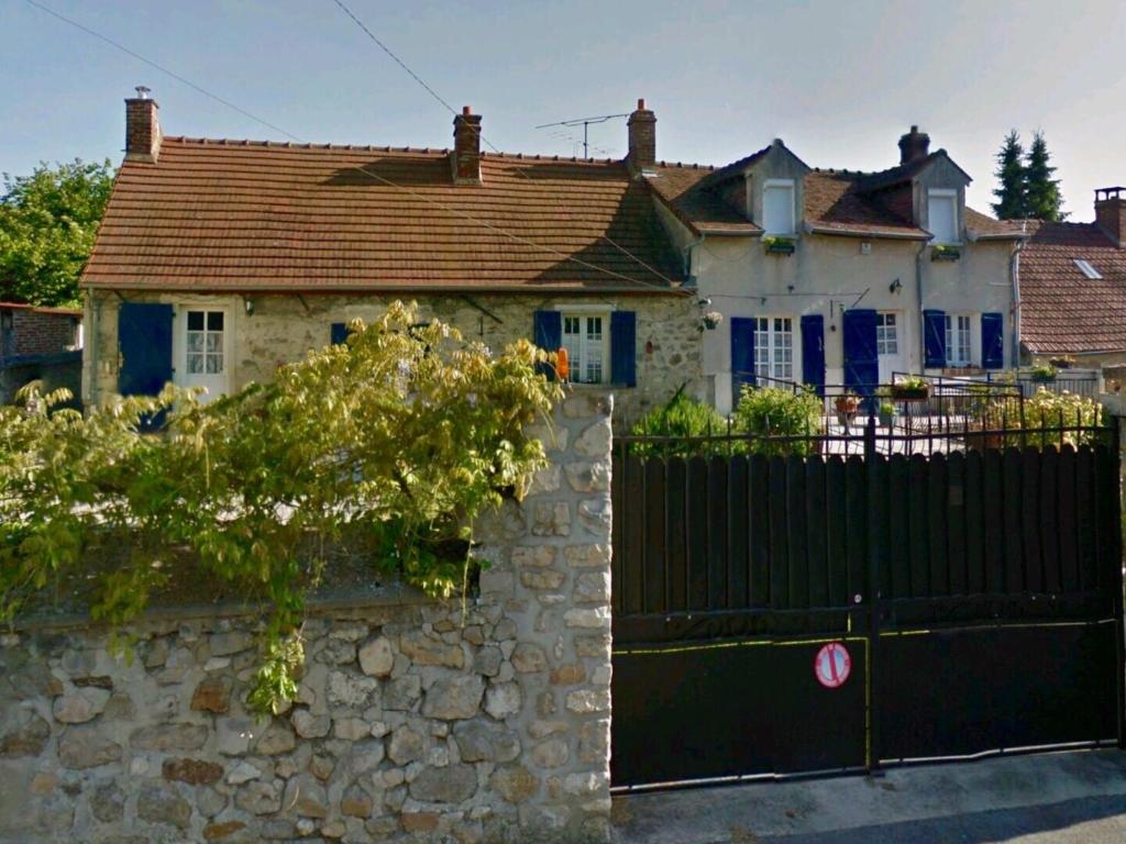 a house with a fence and a stone wall at Chez Madame Titus in Ormoy-Villers