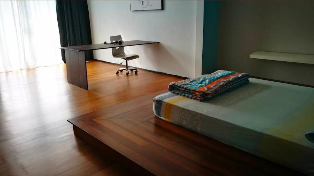 ラワンにあるThe Garden Homestayのデスク、ベッド、デスク、椅子が備わる客室です。