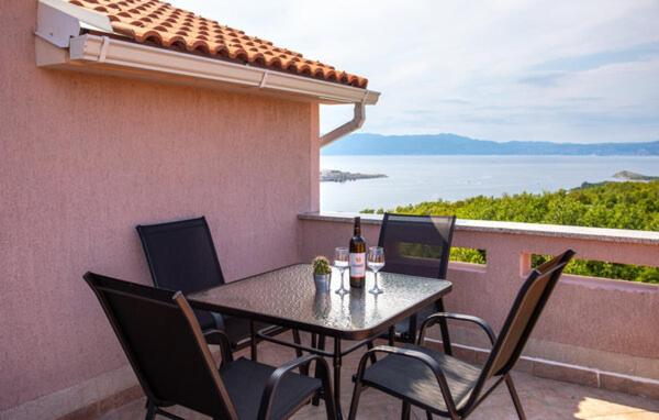 a table and chairs on a balcony with a view of the ocean at Apartman Nika in Omišalj