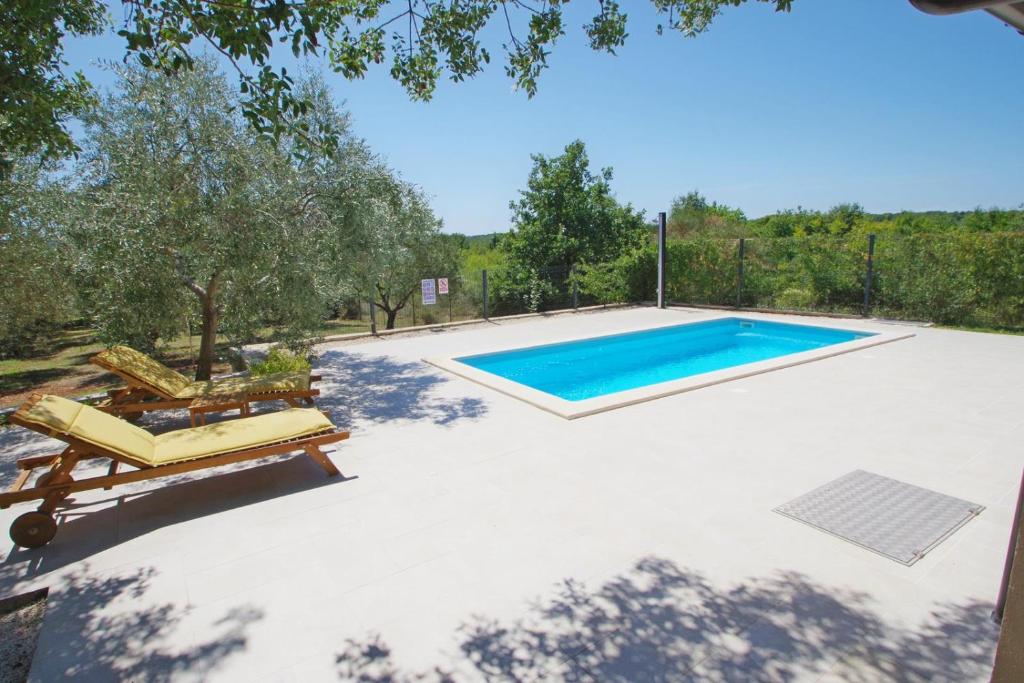 a swimming pool with two lounges and a swimming poolvisor at Holiday house Zara, Pomer in Pomer