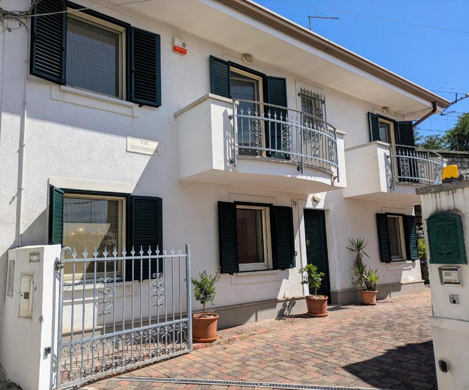 a white house with black shutters and potted plants at Serenissima in Monfalcone