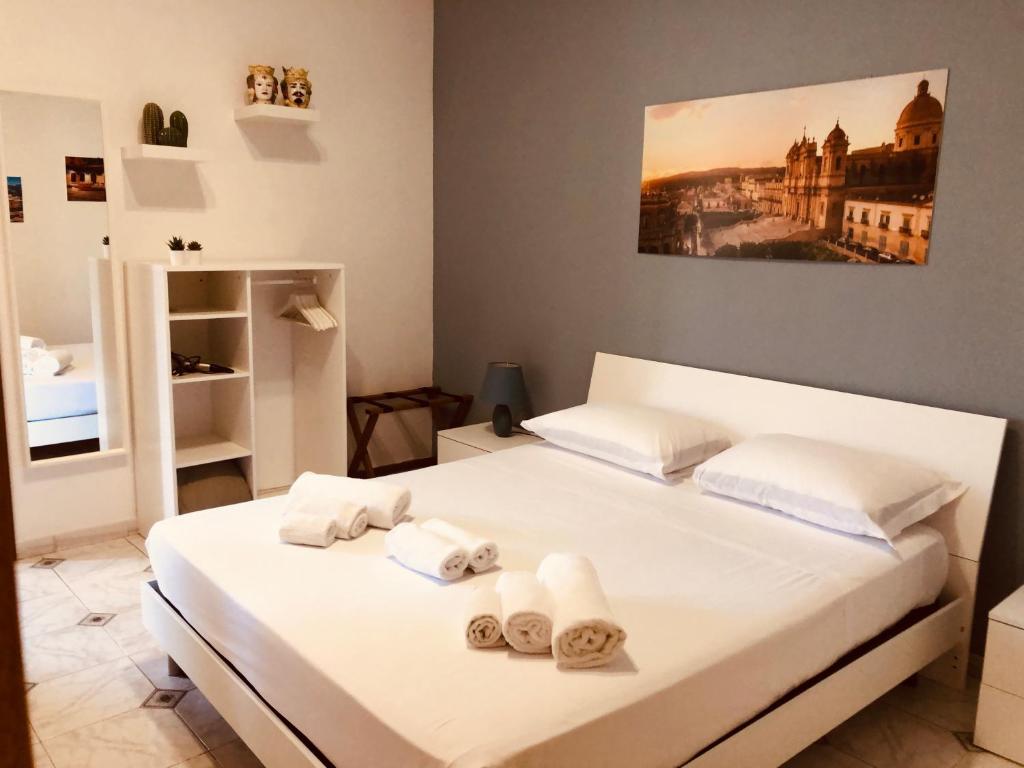 Un dormitorio con una cama blanca con toallas. en La Madonnina, en Noto