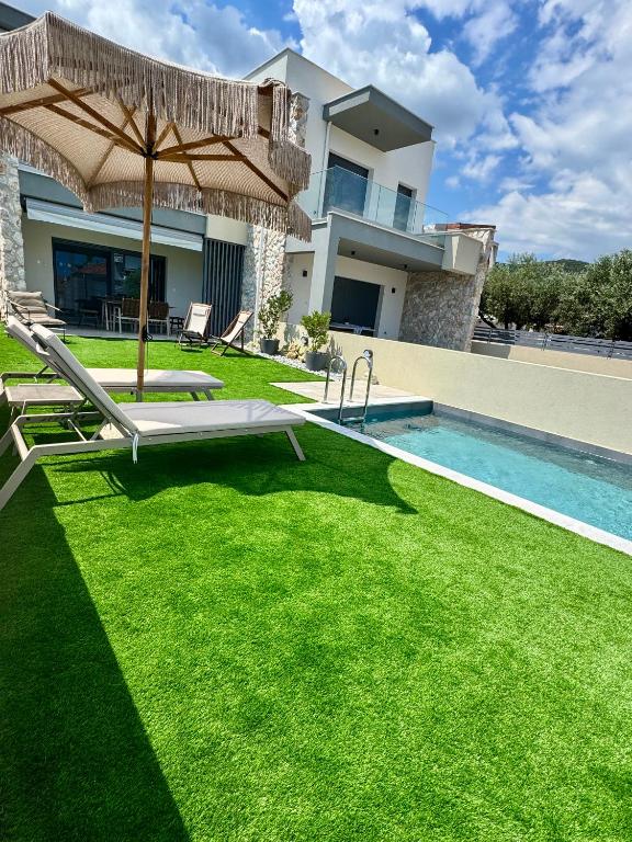 a backyard with a pool and an umbrella and grass at Trinity Pool Villas WHITE in Iraklitsa