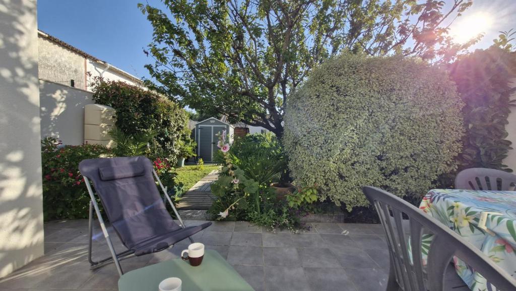 d'une terrasse avec une table, des chaises et un arbre. dans l'établissement Saint Georges de Didonne - PETITE MAISON avec son petit coin de paradis extérieur, à Saint-Georges-de-Didonne