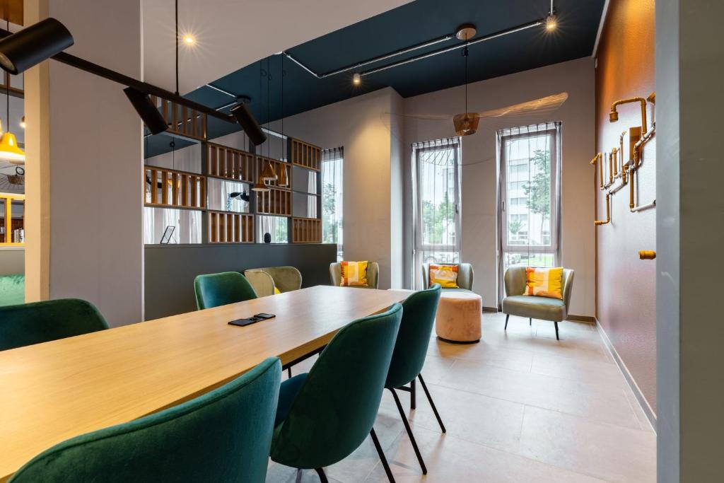 a conference room with a wooden table and green chairs at Holiday Inn - the niu, Pax Berlin Airport by IHG in Berlin