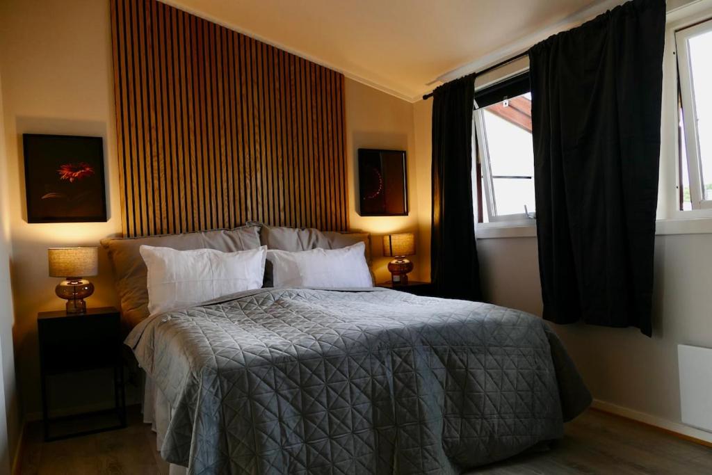 a bedroom with a bed with two windows and two lamps at The Nordic Loft in Oslo