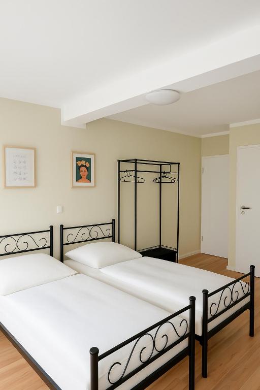 two beds in a bedroom with white walls and wood floors at My Loft in Hagen