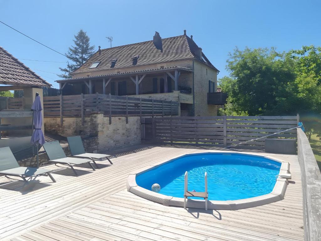 a pool on a deck with chairs and a house at Charmante maison piscine privée in Siorac-en-Périgord