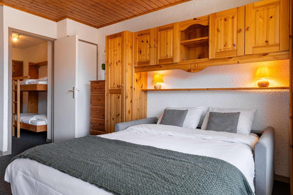 a bedroom with a large bed and wooden cabinets at Cosy Apartment In Heart of Val Thorens, Ski In-Out with WiFi in Val Thorens