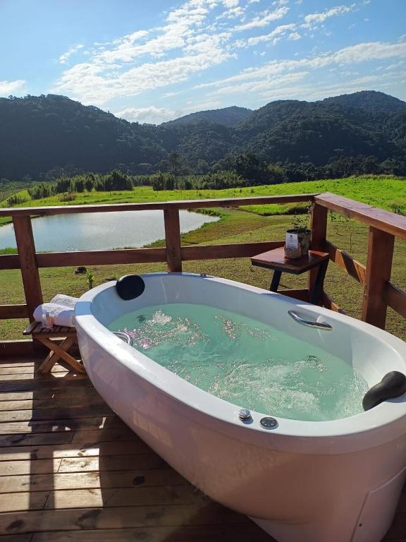a bath tub sitting on a deck next to a body of water at Chalé Refúgio da Coruja in Miracatu