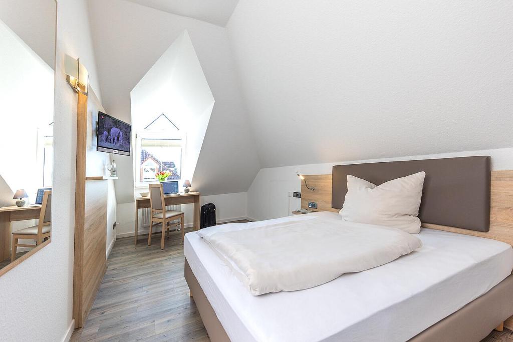 a bedroom with a white bed and a table and a desk at Hotel Casa Nostra in Schloß Holte-Stukenbrock