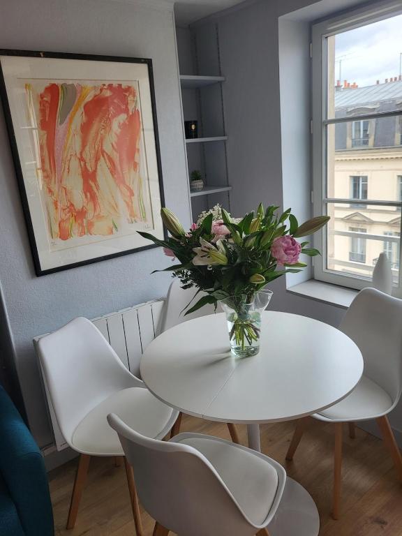 a white table and chairs with a vase of flowers at Le petit versaillais in Versailles