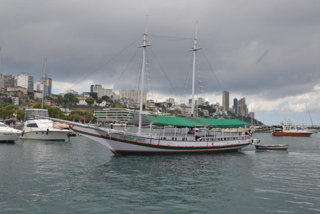 Un velero atracado en un puerto con una ciudad en Escunha, en Salvador