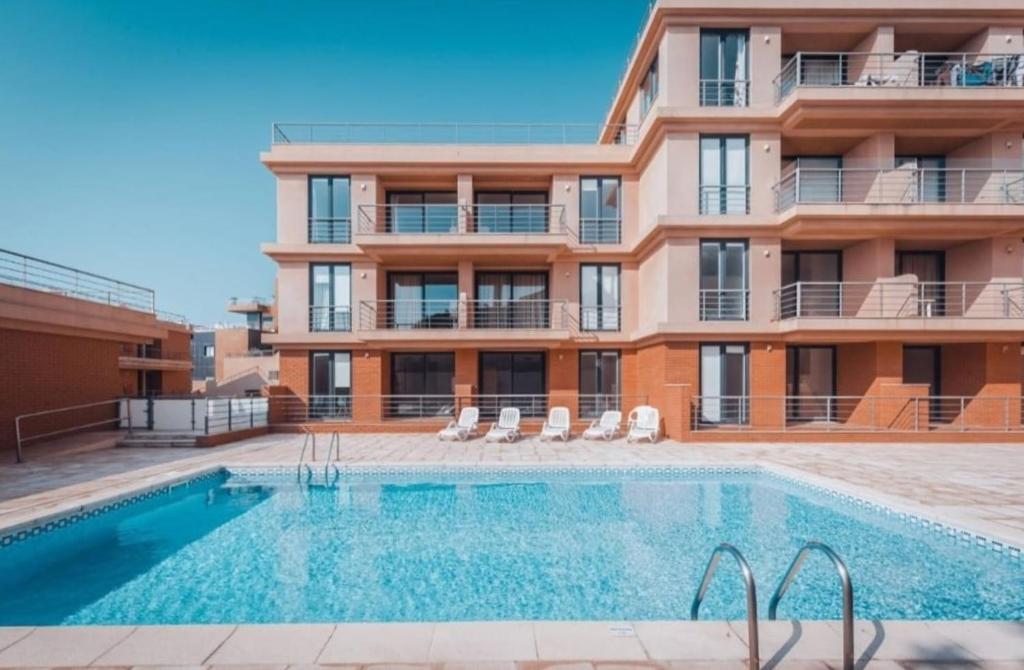 a building with a swimming pool in front of a building at Heart Stone by the Sea in Lourinhã