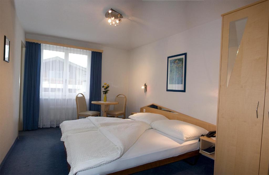 een slaapkamer met een wit bed en een raam bij Hotel Alpha in Saas-Grund