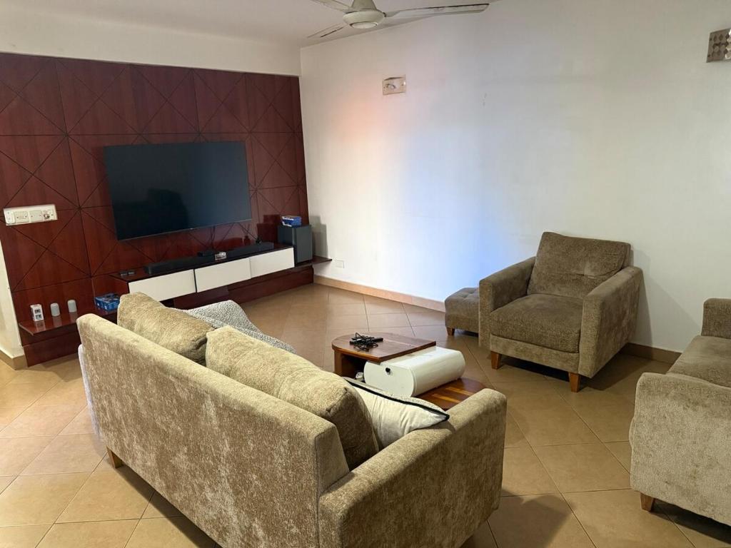 a living room with two couches and a flat screen tv at HEILiG HOUSE in Dar es Salaam