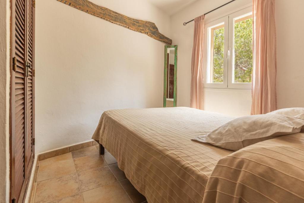 un dormitorio con una cama y una ventana en Can Solsulet, en Es Pujols