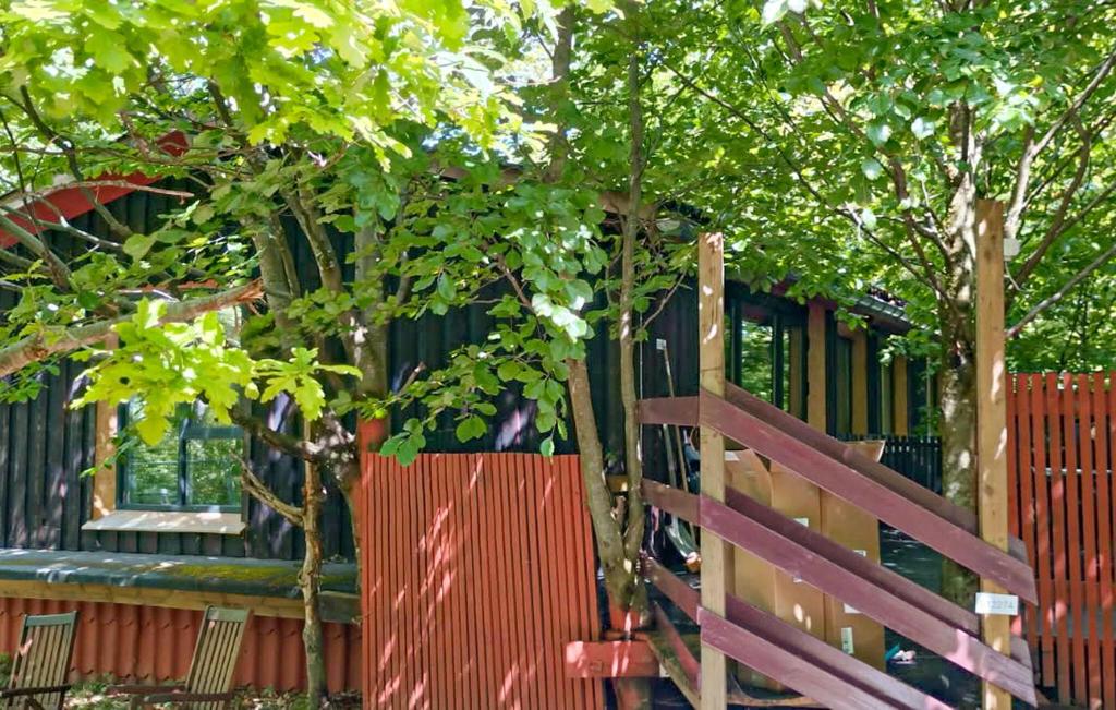 a fence with a tree in front of a house at Stunning Apartment In Åsljunga in Åsljunga