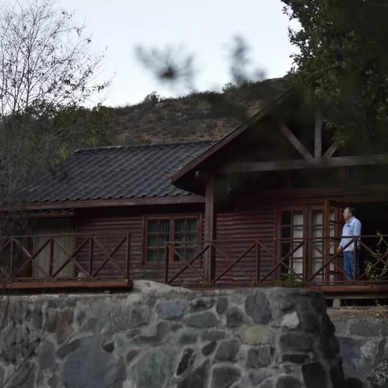 a man standing on the porch of a house at Cabañas Ocoa in Hijuelas