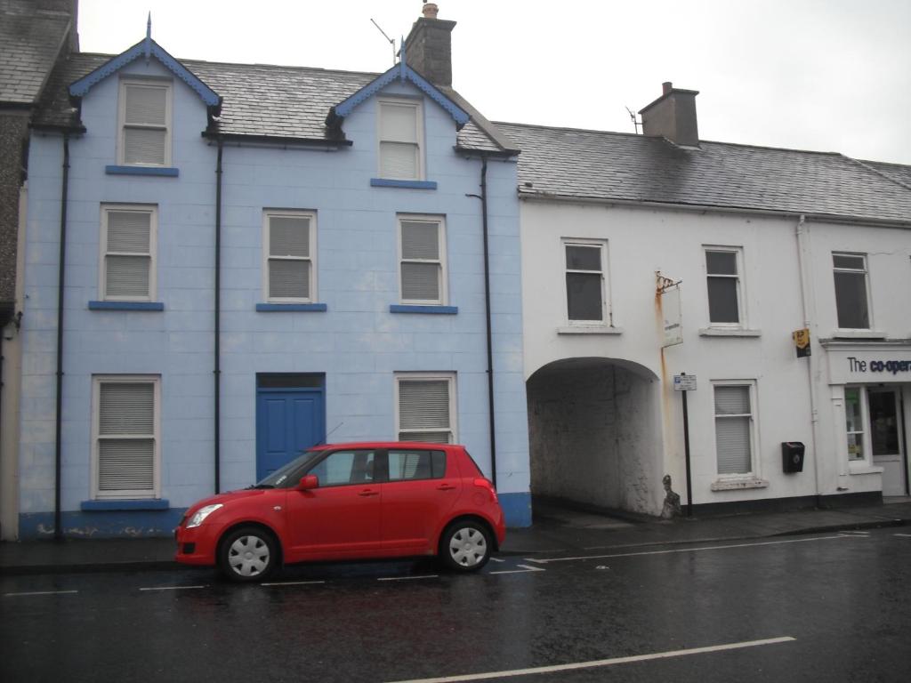 un coche rojo estacionado frente a un edificio en The Blue House Apartments en Bushmills