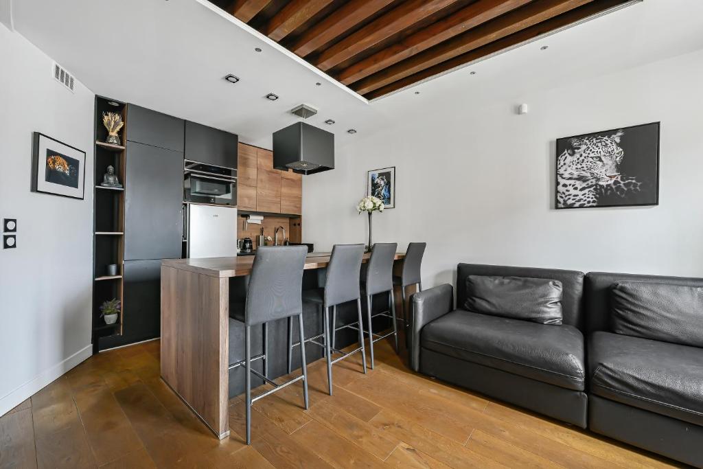 eine Küche und ein Wohnzimmer mit einer Bar und einem Sofa in der Unterkunft Le Sorrento - 2 prs - Métro 12 - Proche Paris in Vanves