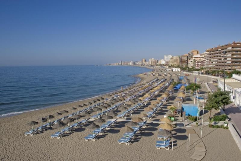 a beach with chairs and umbrellas and the ocean at La Cabane Fuengirola in Fuengirola