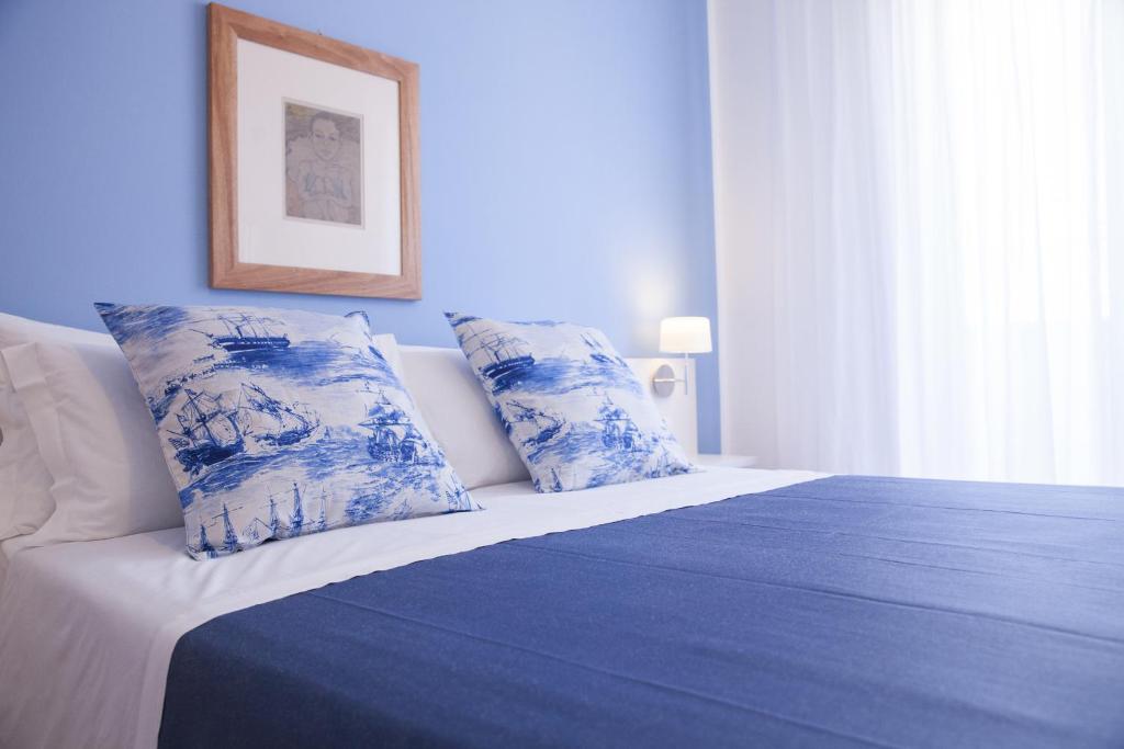 a blue and white bed with two pillows on it at B&B L'Artista in Portopalo