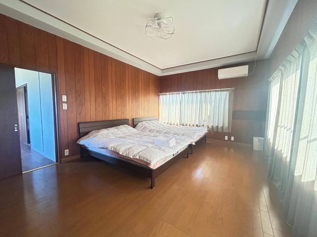 une chambre avec un lit dans une pièce aux murs en bois dans l'établissement Jun resort 梅, à Kujukuri