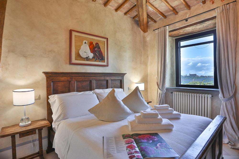 a bedroom with a large white bed with a window at Torre Collevento Luxury Villa in Orvieto
