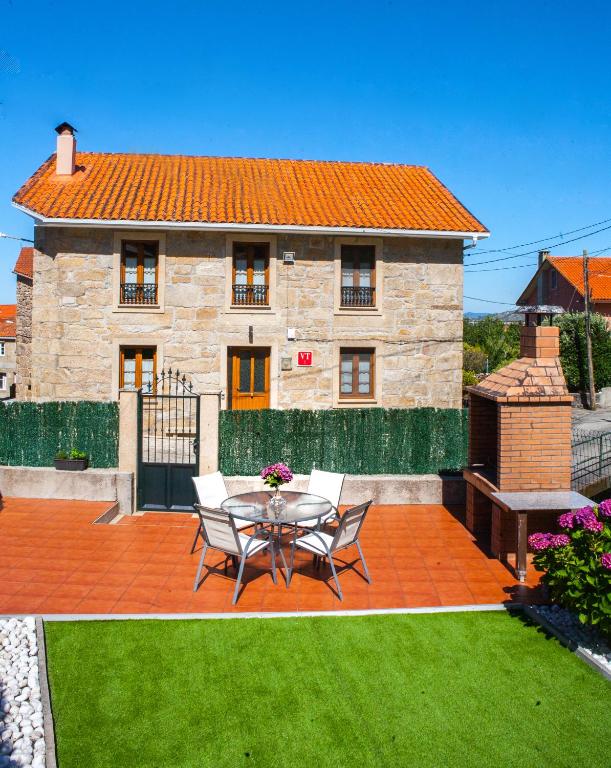 a patio with a table and chairs in front of a house at Casa De Rama in San Mamede de Carnota