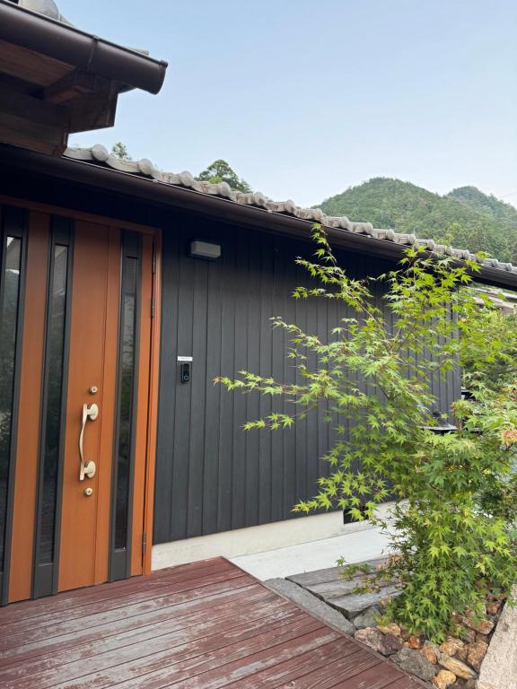 een huis met een zwarte garage met een houten deur bij Three Field Tamba-Sasayama in Sasayama