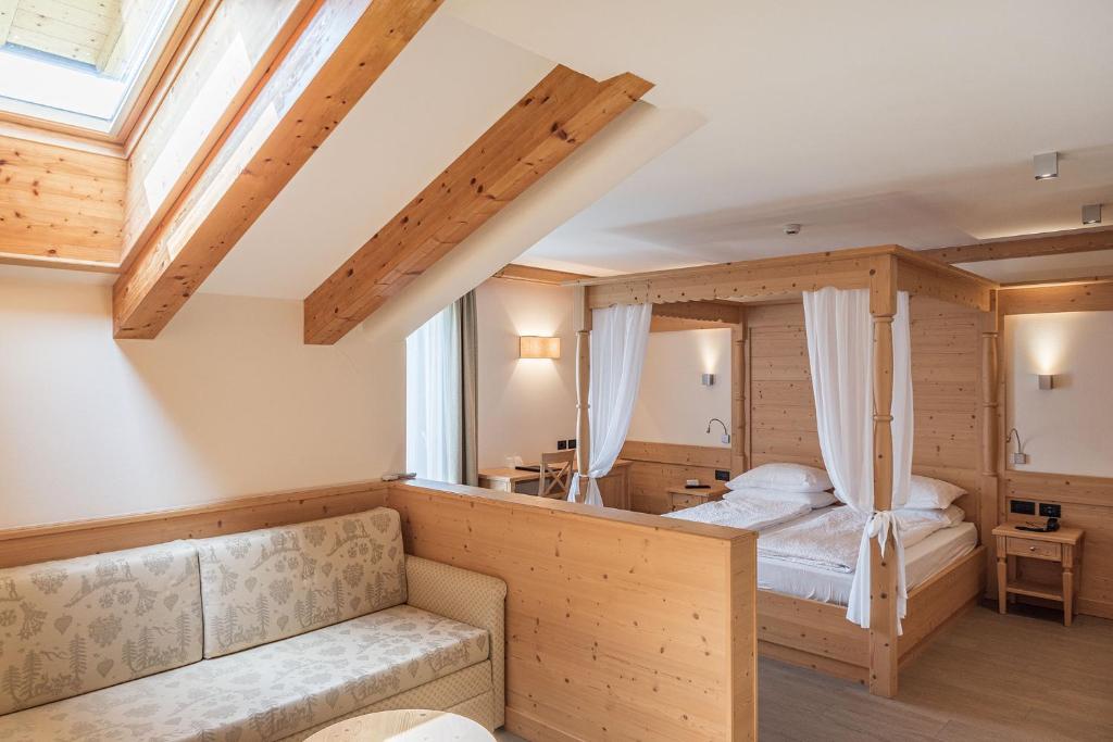 a bedroom with a bed and a couch at Hotel Garnì Paradisi - Wellness & Spa in Mezzano