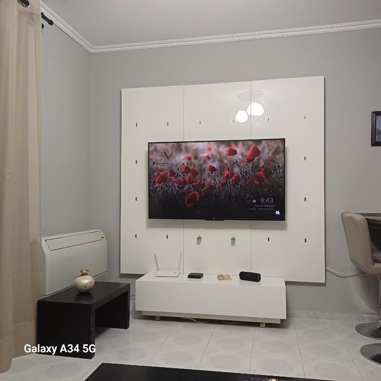 a living room with a tv on a white wall at Cleopatra Apartment in Himare