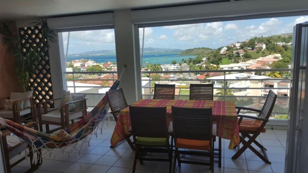 ein Esszimmer mit einem Tisch und Stühlen sowie einem Balkon in der Unterkunft kay betty in Les Trois-Îlets