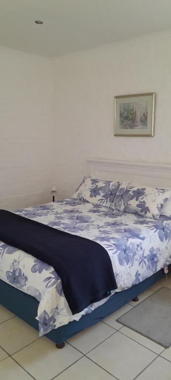 a bed with a blue and white comforter on it at Our Little House in Franskraalstrand