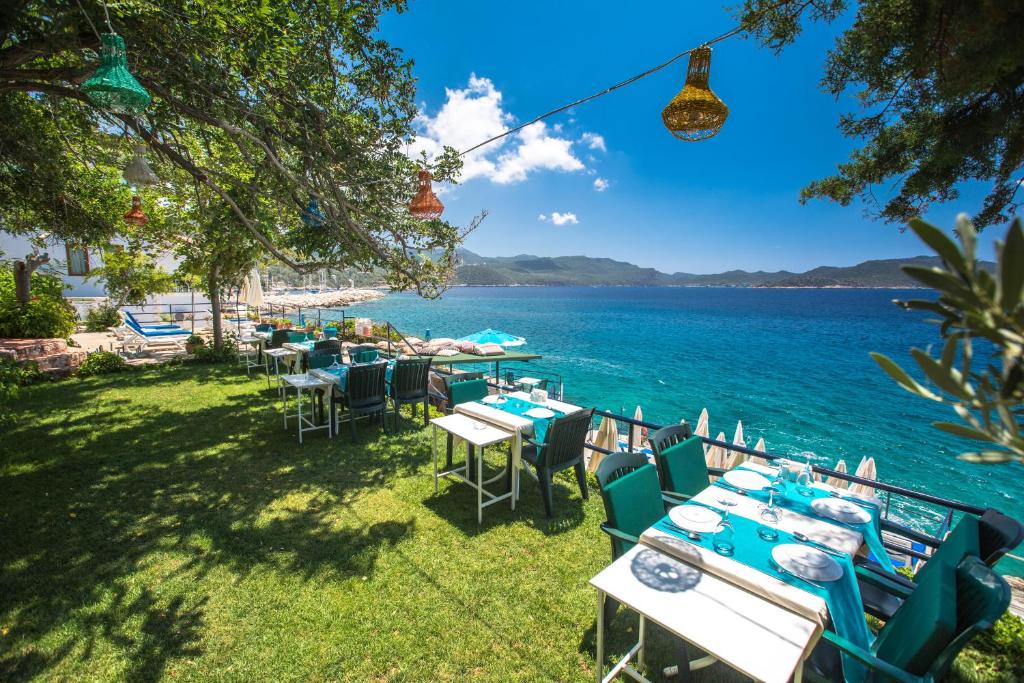 a group of tables and chairs next to the water at Sardunya Andifli Otel in Kas
