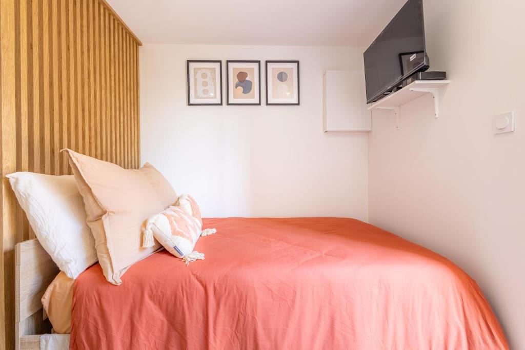 a small bedroom with a bed with orange sheets at Studio cosy proche Bordeaux in Ambarès-et-Lagrave