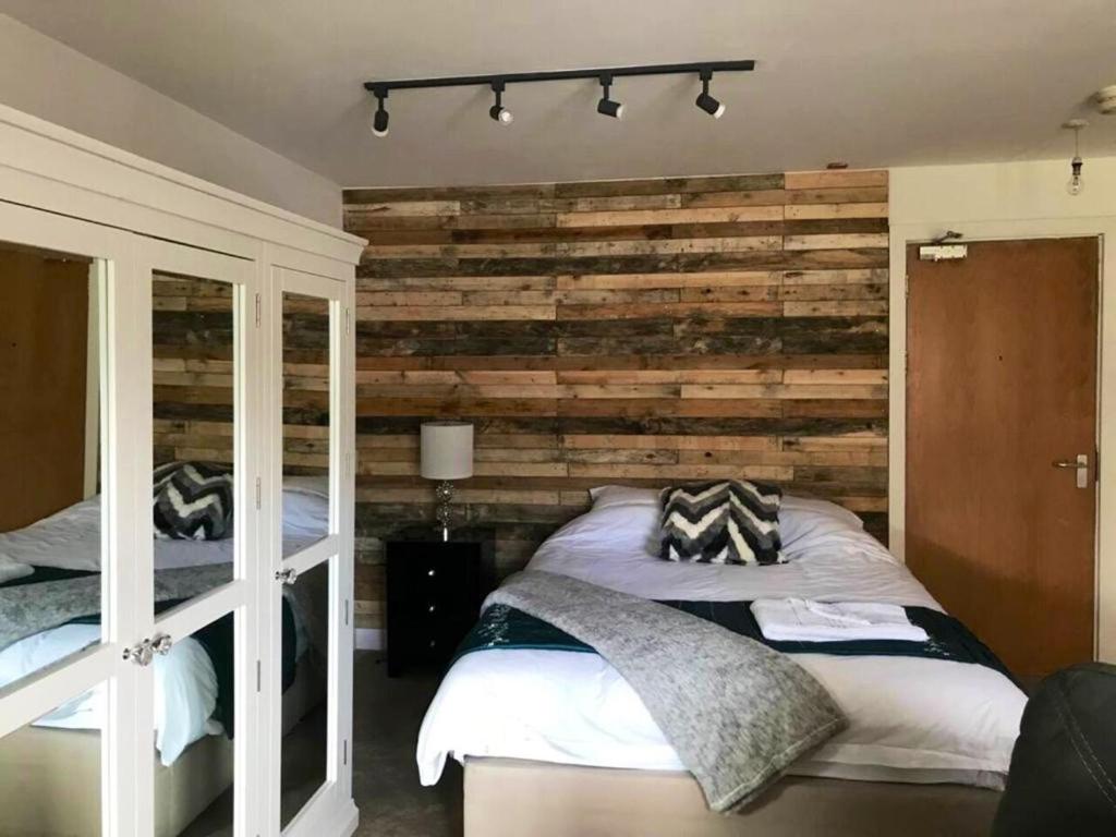 a bedroom with two beds and a wooden wall at City studio Apartment in Swansea