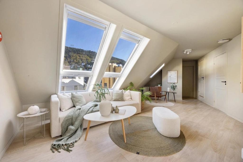 a living room with a couch and two tables and large windows at Top-Floor Gem with City Views in Bergen