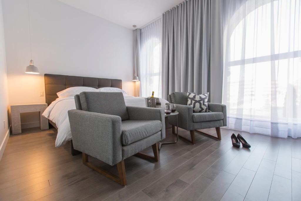 um quarto com uma cama, 2 cadeiras e uma mesa em Hotel Oui GO! em Trois-Rivières