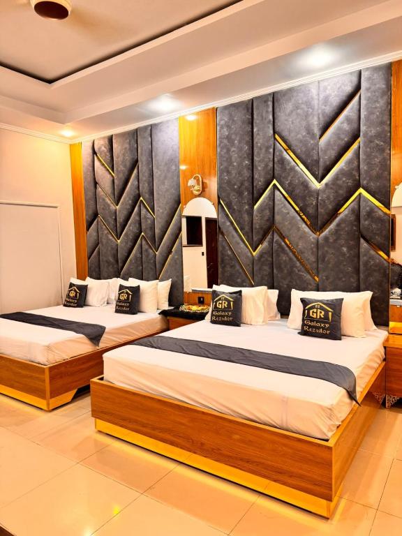 a bedroom with two beds and a wall at Galaxy Rezidor in Karachi