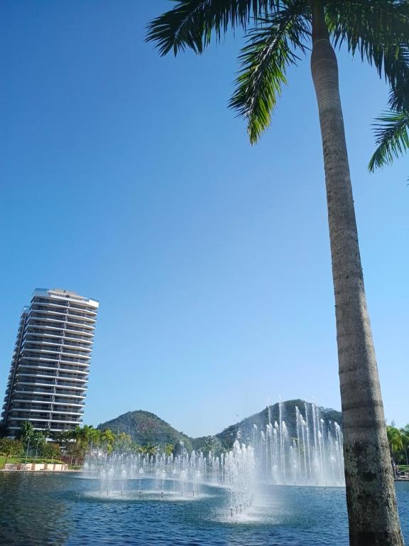 a fountain in front of a building and palm trees at Apart Hotel Barra Bela Barra da Tijuca in Rio de Janeiro